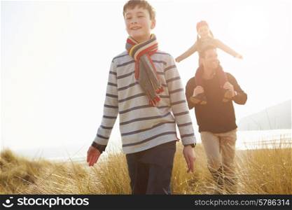 Father And Children Walking Through Dunes On Winter Beach