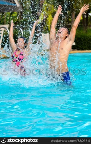 Father and daughter are having fun splashing in the pool