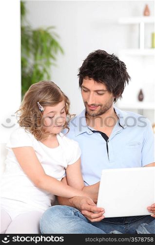 Father and daughter at home with a laptop