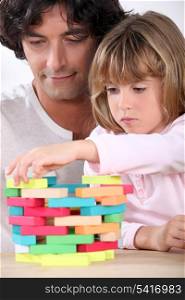 Father and daughter building a tower of blocks