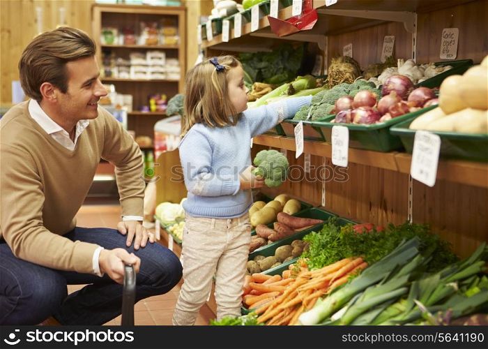 Father And Daughter Choosing Fresh Vegetables In Farm Shop