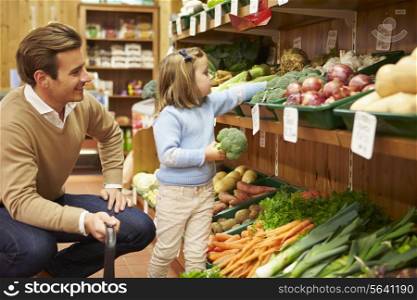 Father And Daughter Choosing Fresh Vegetables In Farm Shop