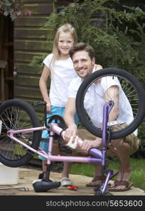 Father And Daughter Cleaning Bike Together