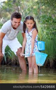 Father and daughter fishing in pond