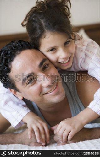 Father and daughter girl relaxing on bed in bedroom smiling (selective focus)