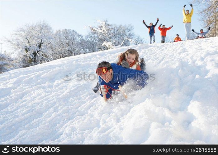 Father And Daughter Having Fun Sledging Down Hill