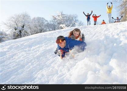 Father And Daughter Having Fun Sledging Down Hill
