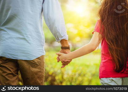 Father and daughter holding hands and walking in the park in summer. Love, family and sharing concept.