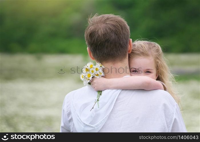 Father and daughter in big camomile mountain meadow. Emotional, love and care scene.
