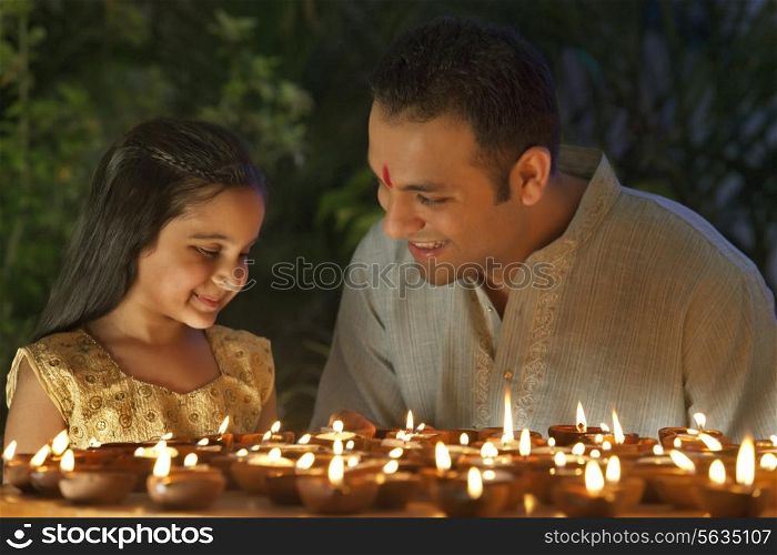 Father and daughter lighting diyas
