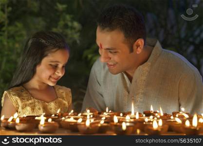 Father and daughter lighting diyas