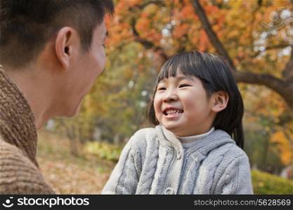 Father and daughter looking at each other in the park, autumn