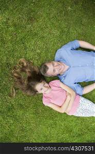 Father and daughter lying on grass