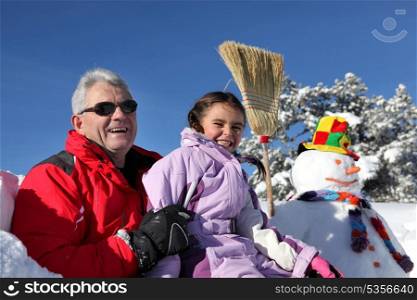 Father and daughter making a snowman