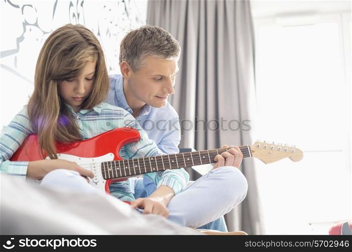 Father and daughter playing electric guitar at home