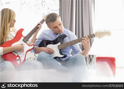 Father and daughter playing electric guitars at home