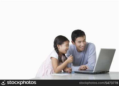 Father and daughter playing with laptop on kitchen counter