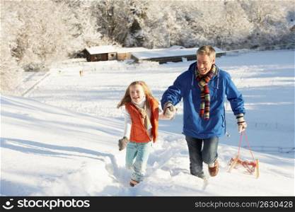 Father And Daughter Pulling Sledge Up Snowy Hill