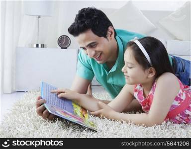 Father and daughter reading story book while lying on rug at home