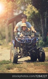 father and daughter riding on quad atv on dirt field