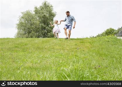 Father and daughter running downhill