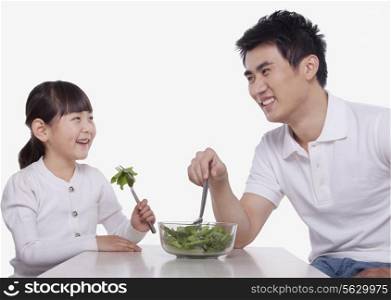 Father and Daughter sharing a salad, studio shot