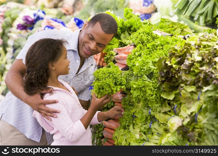 Father and daughter shopping for lettuce at a grocery store
