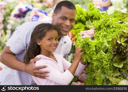 Father and daughter shopping for lettuce at a grocery store