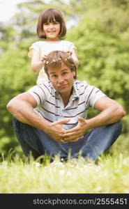 Father and daughter sitting outdoors with flowers smiling