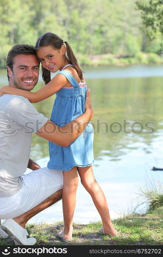 Father and daughter standing on a riverbank