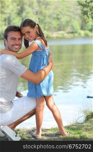 Father and daughter standing on a riverbank