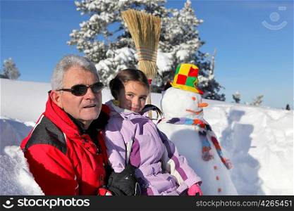 Father and daughter stood by snowman