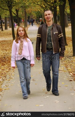 Father and daughter taking a walk in an autumn park