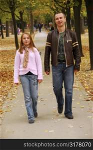 Father and daughter taking a walk in an autumn park