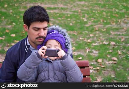 Father And Daughter Taking Photographs At The Park