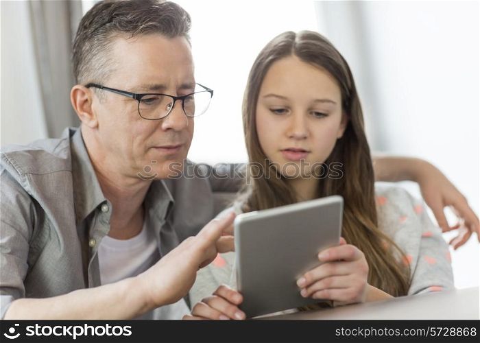 Father and daughter using digital tablet at home