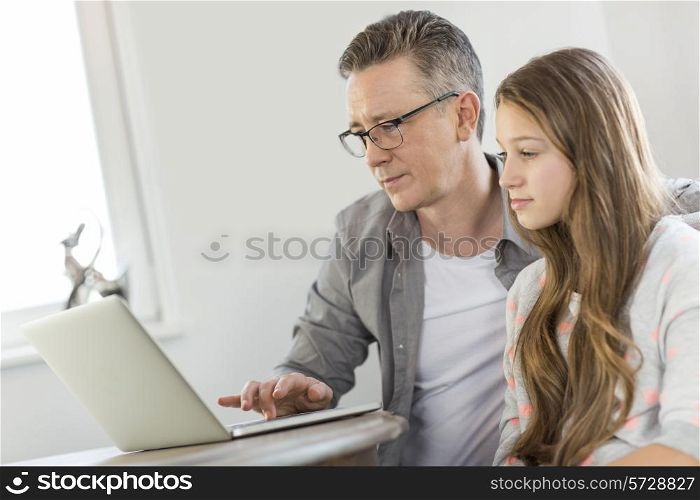 Father and daughter using laptop at home