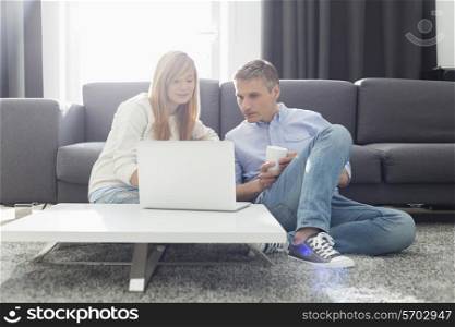 Father and daughter using laptop in living room