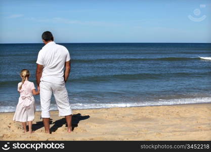 Father and daughter watching the horizon at the beach