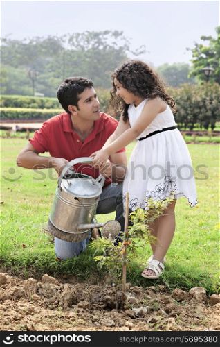 Father and daughter watering plants