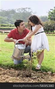Father and daughter watering plants