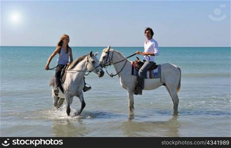father and daughter with arabian and camargue horses in the sea with an evening sun