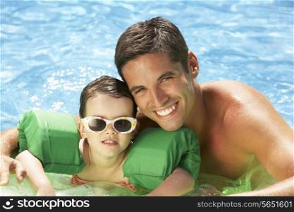 Father And Daughter With Armbands In Swimming Pool