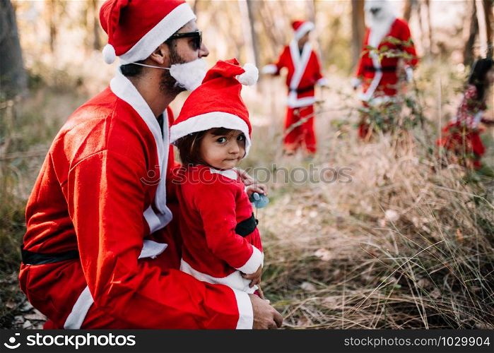 Father and daughter with group of people disguised to christmas walking and enjoying through the forest
