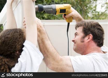 Father and daughter working on home improvement project. He&rsquo;s using the drill.