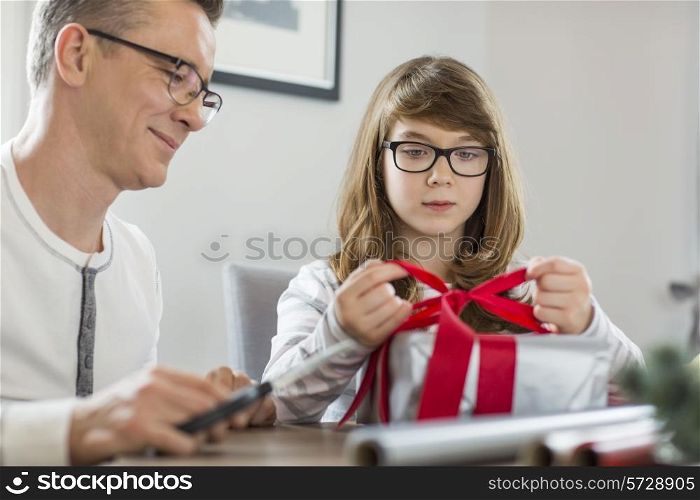 Father and daughter wrapping Christmas present at home