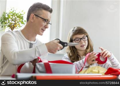 Father and daughter wrapping Christmas presents at home