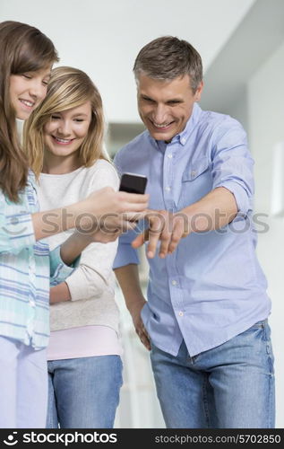 Father and daughters using smart phone at home