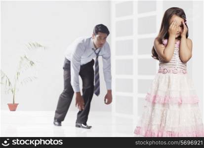 Father and girl playing hide and seek game at home