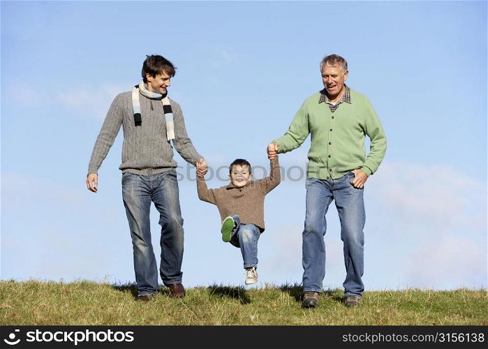 Father And Grandfather Swinging Young Boy